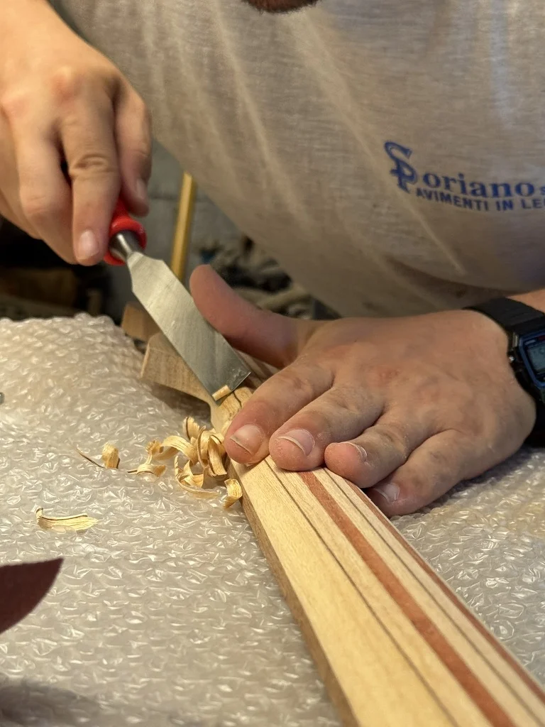 Mani che intagliano a mano libera la voluta sul retro della paletta del manico Precision Bass in ramino e padouk