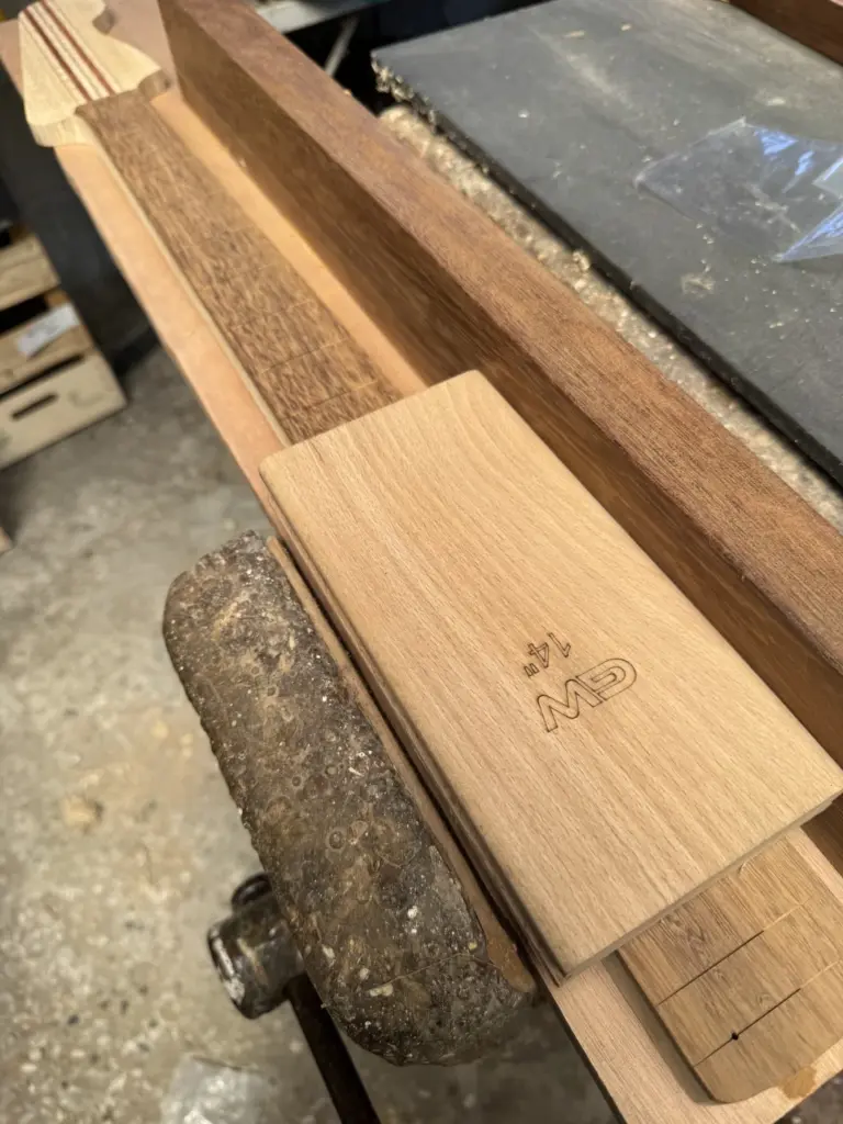 Radius sanding block da 14 pollici appoggiato su tastiera in iroko durante la raggiatura del Precision Bass